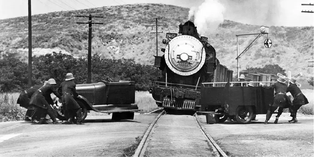 Steam locomotive pulling a train past workers and equipment in a rural landscape