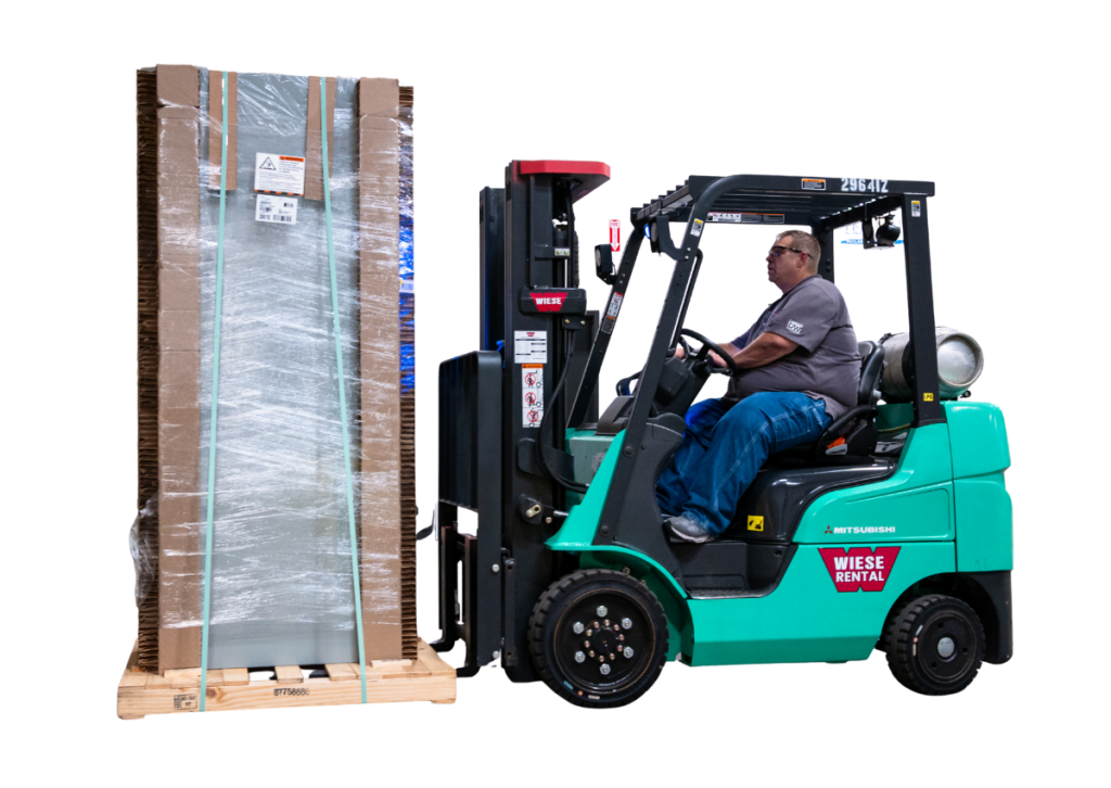 Forklift lifting a tall wrapped pallet beside a worker in a teal forklift