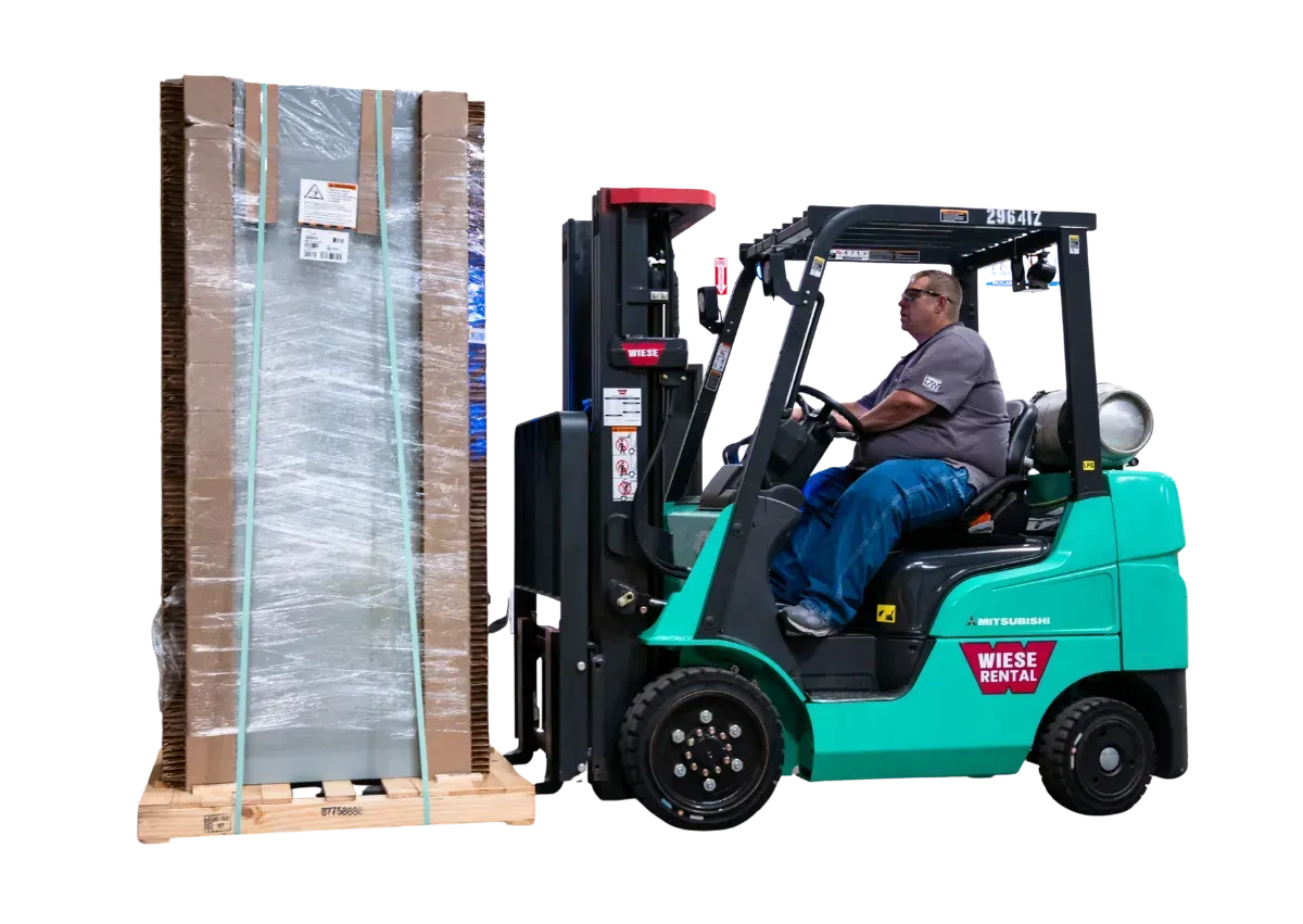 Forklift lifting a shrink-wrapped pallet of boxes in a warehouse.