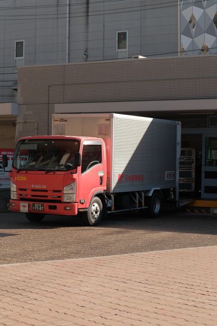 Red cargo truck parked at a building loading dock with its rear cargo door open
