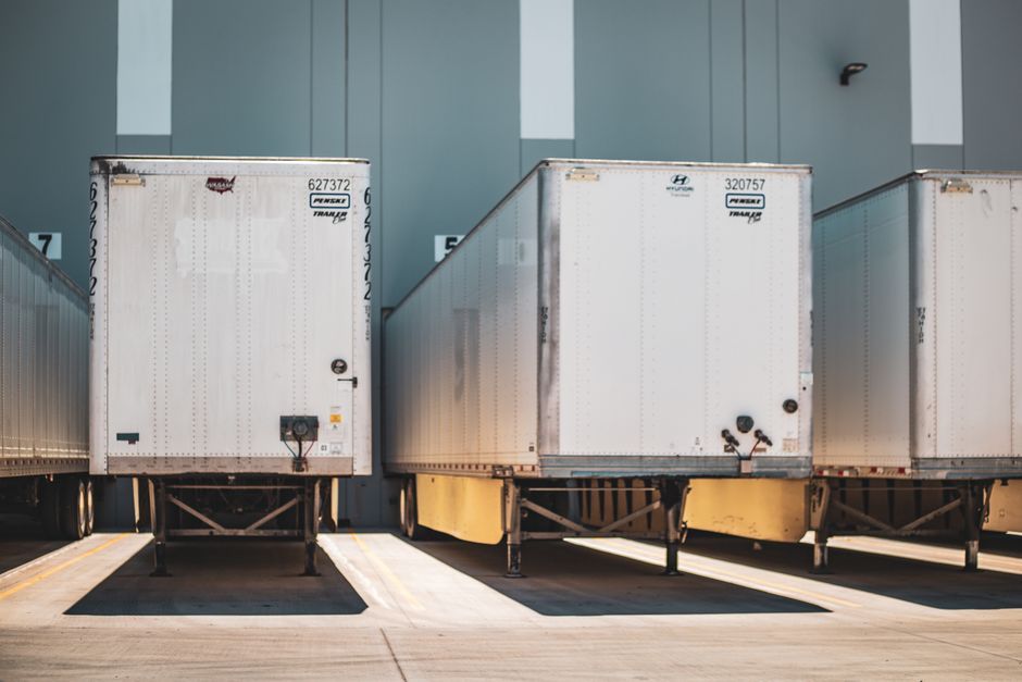 White freight trailers parked at a loading dock beside a warehouse building
