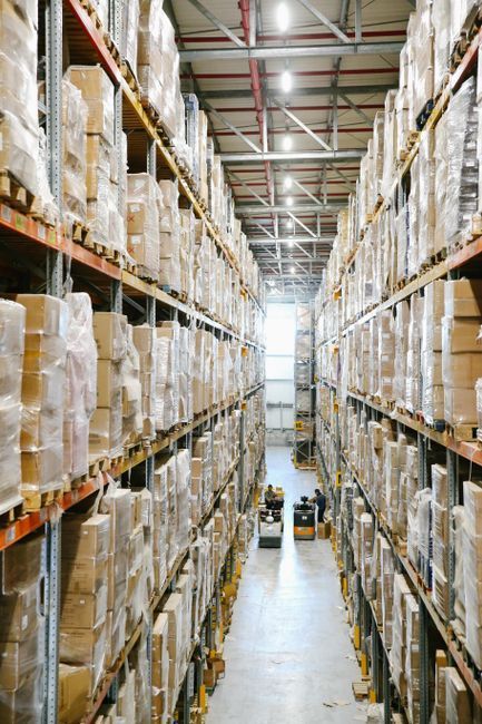 Tall warehouse aisle lined with stacked pallet boxes on metal shelves