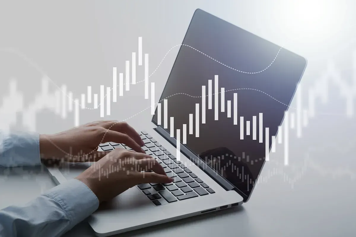 Hands typing on a laptop with a white analytics graph overlay on a gray background