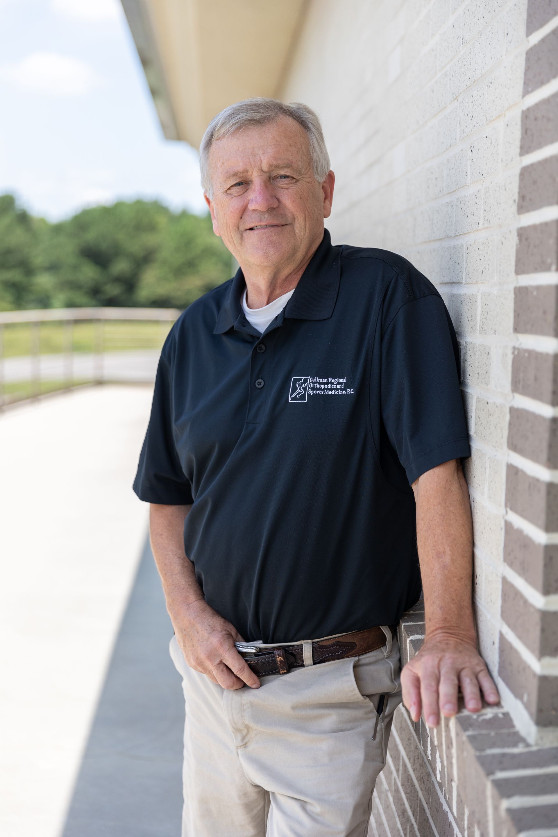 Dr. David Dueland in a blue shirt is leaning on a railing and smiling.