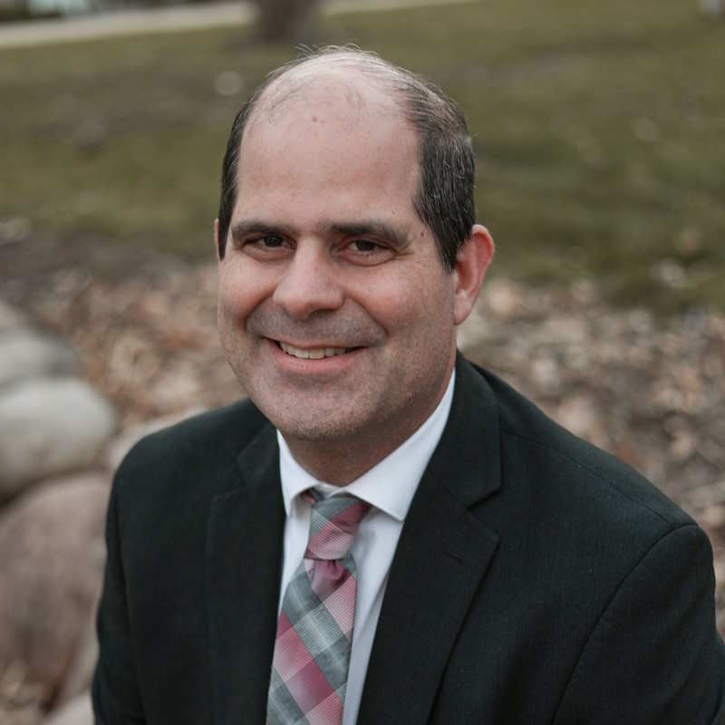 Man in suit smiling outdoors.
