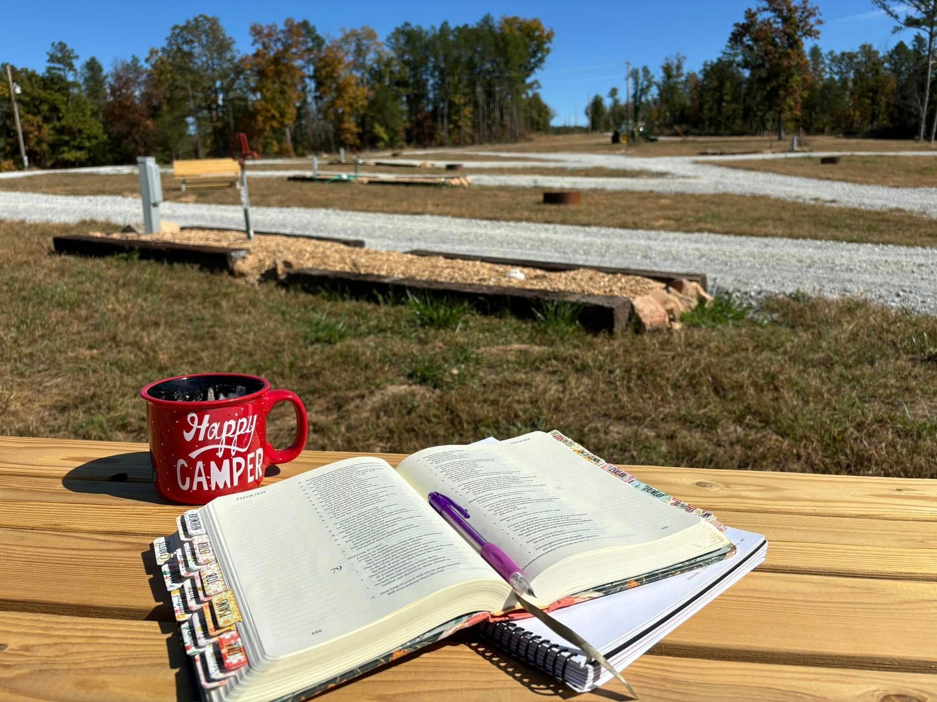 A cup of coffee and a notebook are on a wooden table.