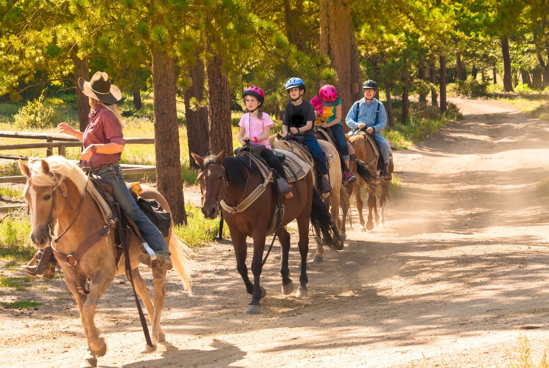 A group of people are riding horses down a dirt road.