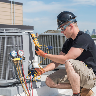 HVAC technician inspecting air conditioning unit on a rooftop using a multimeter.