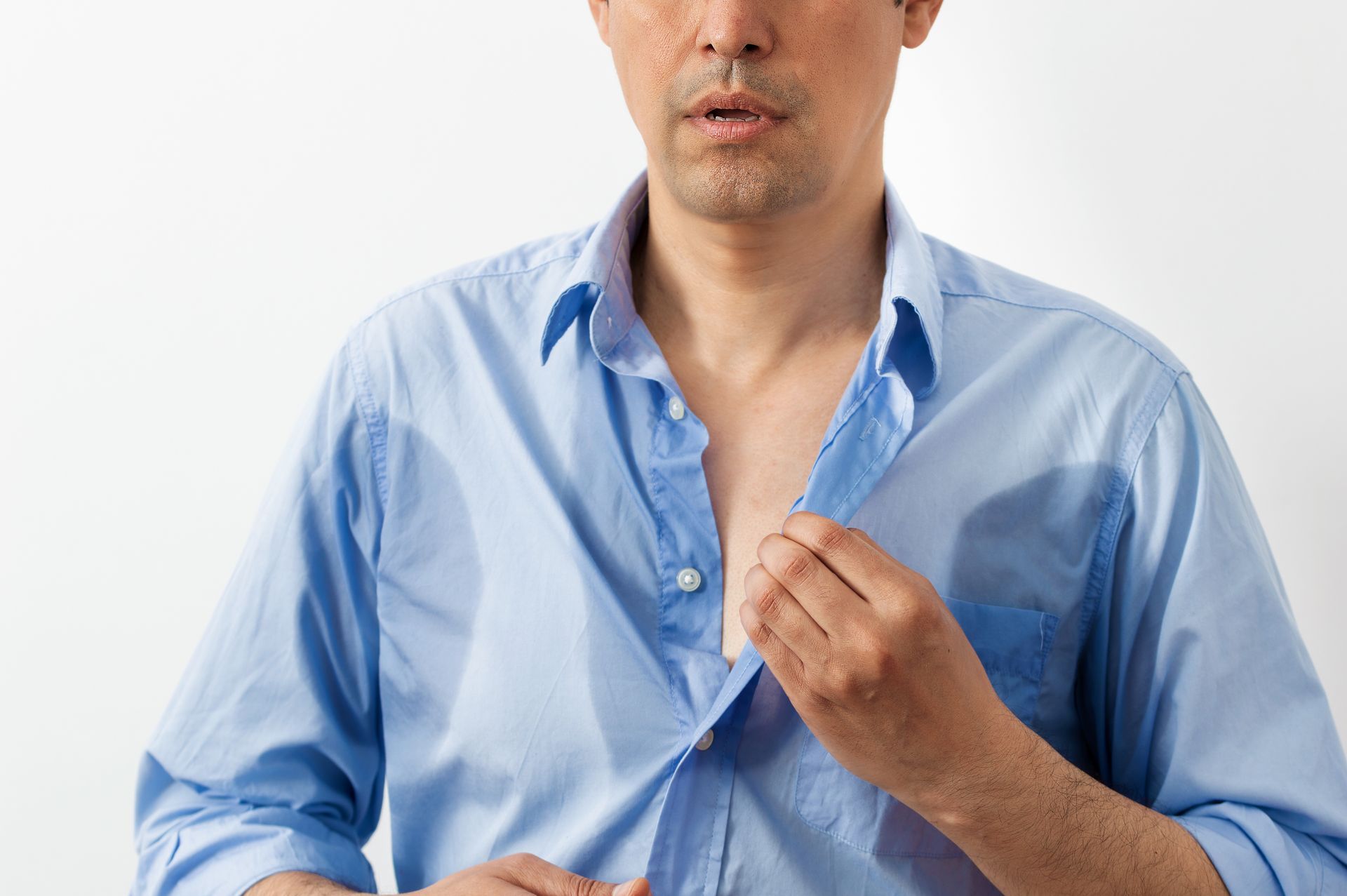 Man mit verschwitztem blauem Hend. Schweißflecken sind unter den Achseln und auf der Brust zu sehen.