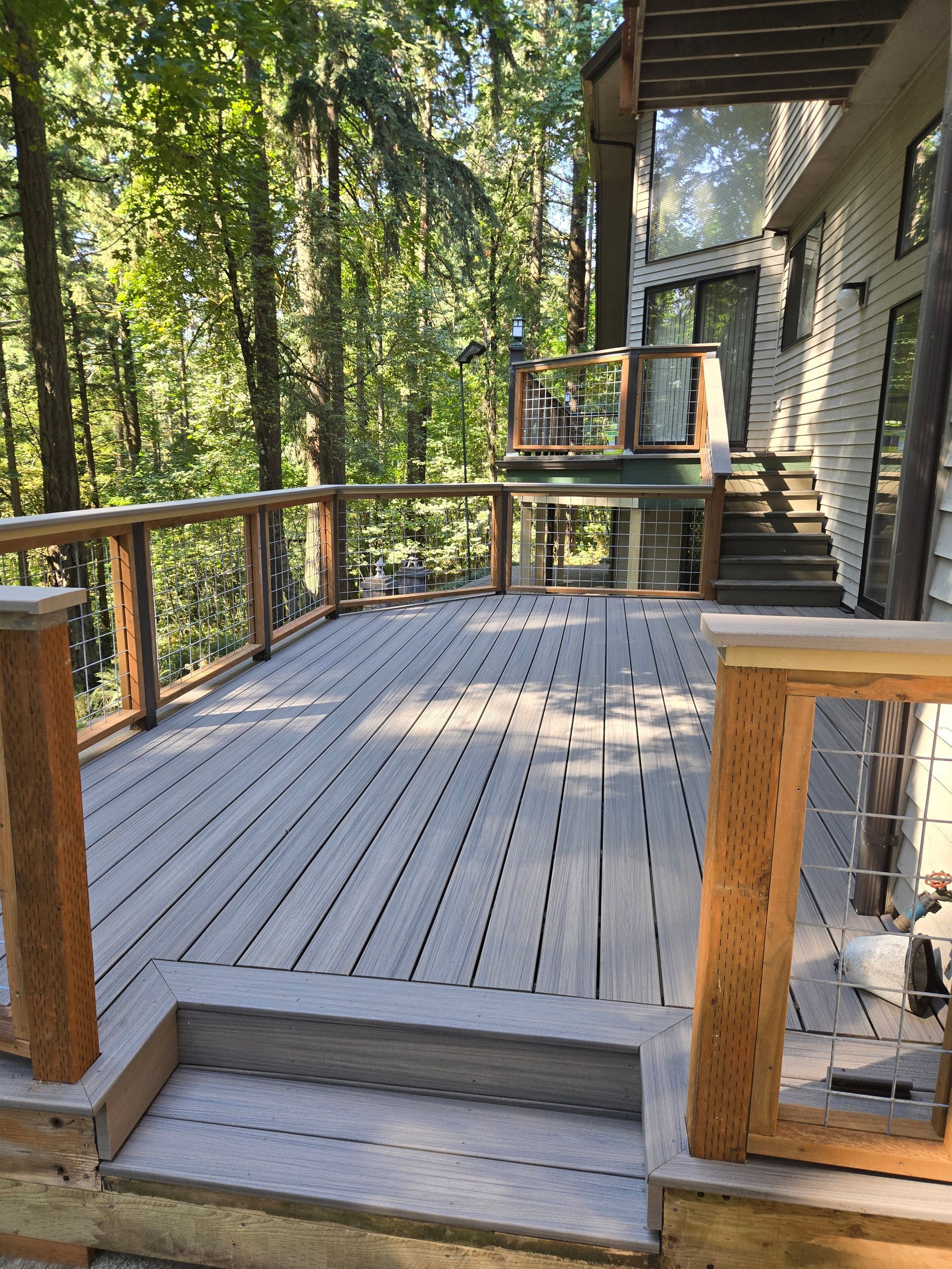 Wooden deck with railings and steps overlooking a wooded yard