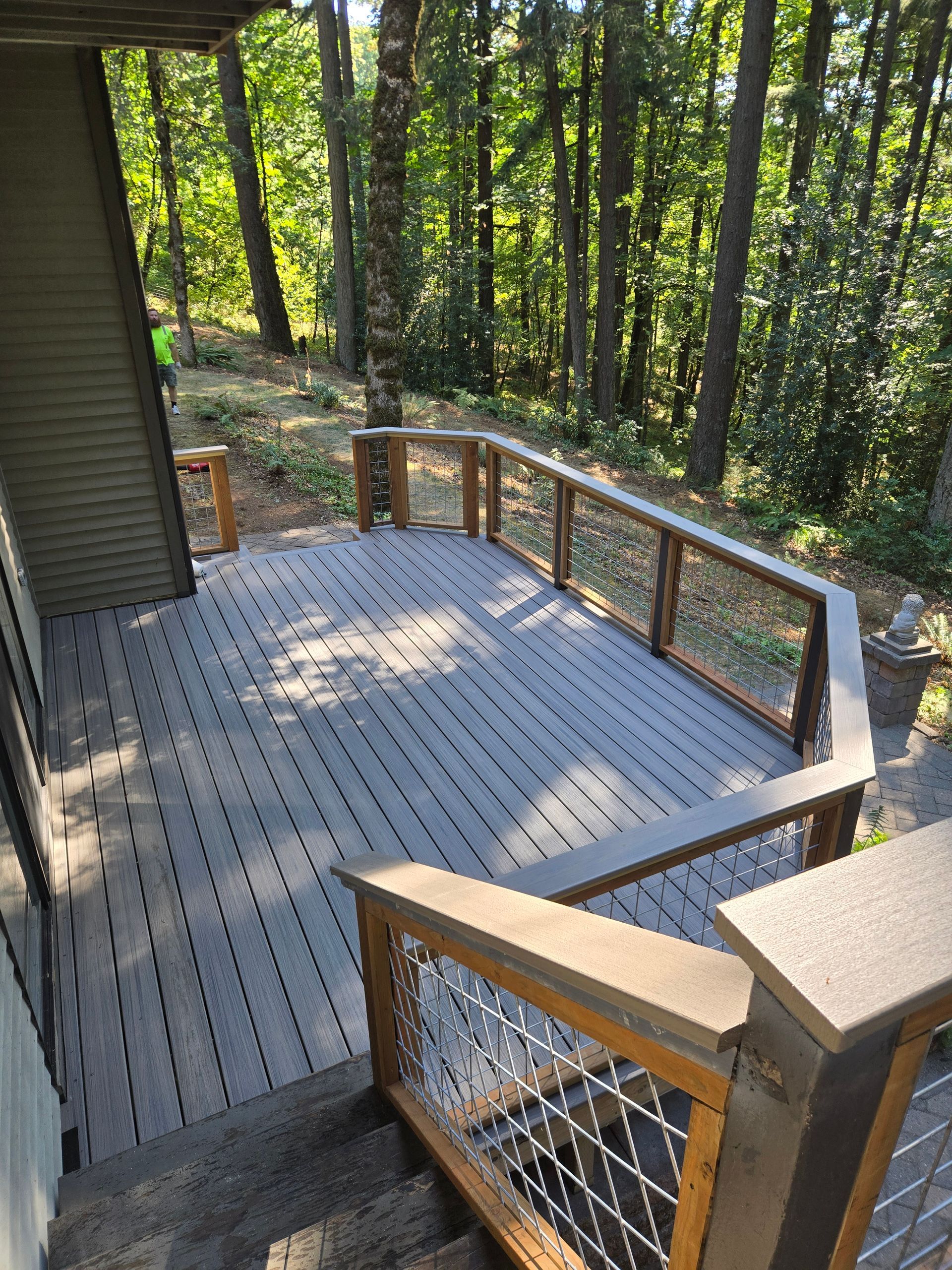 Wooden deck with railings overlooking a wooded backyard in dappled sunlight