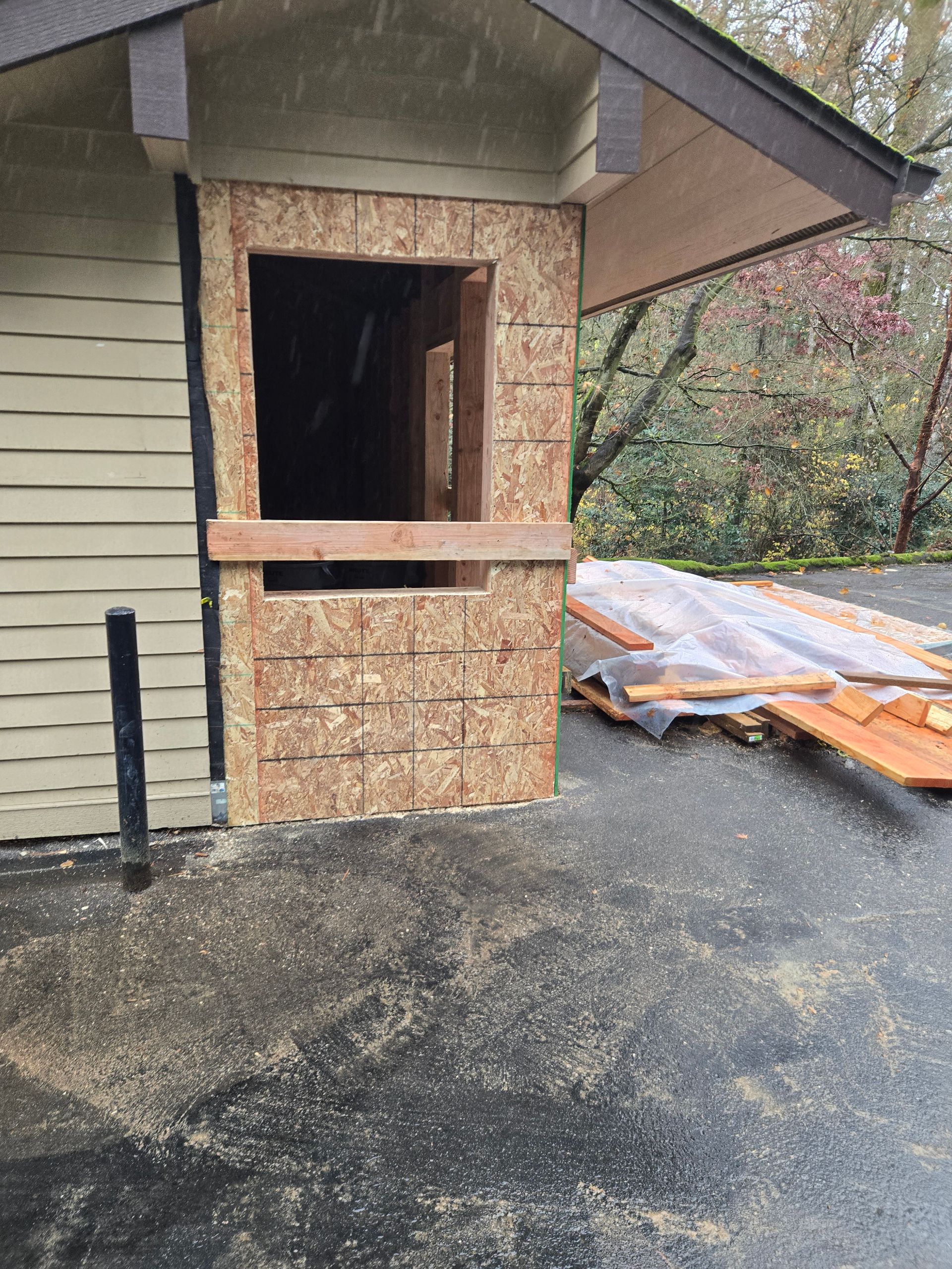 Partially boarded-up doorway on a house with plywood and construction debris outside
