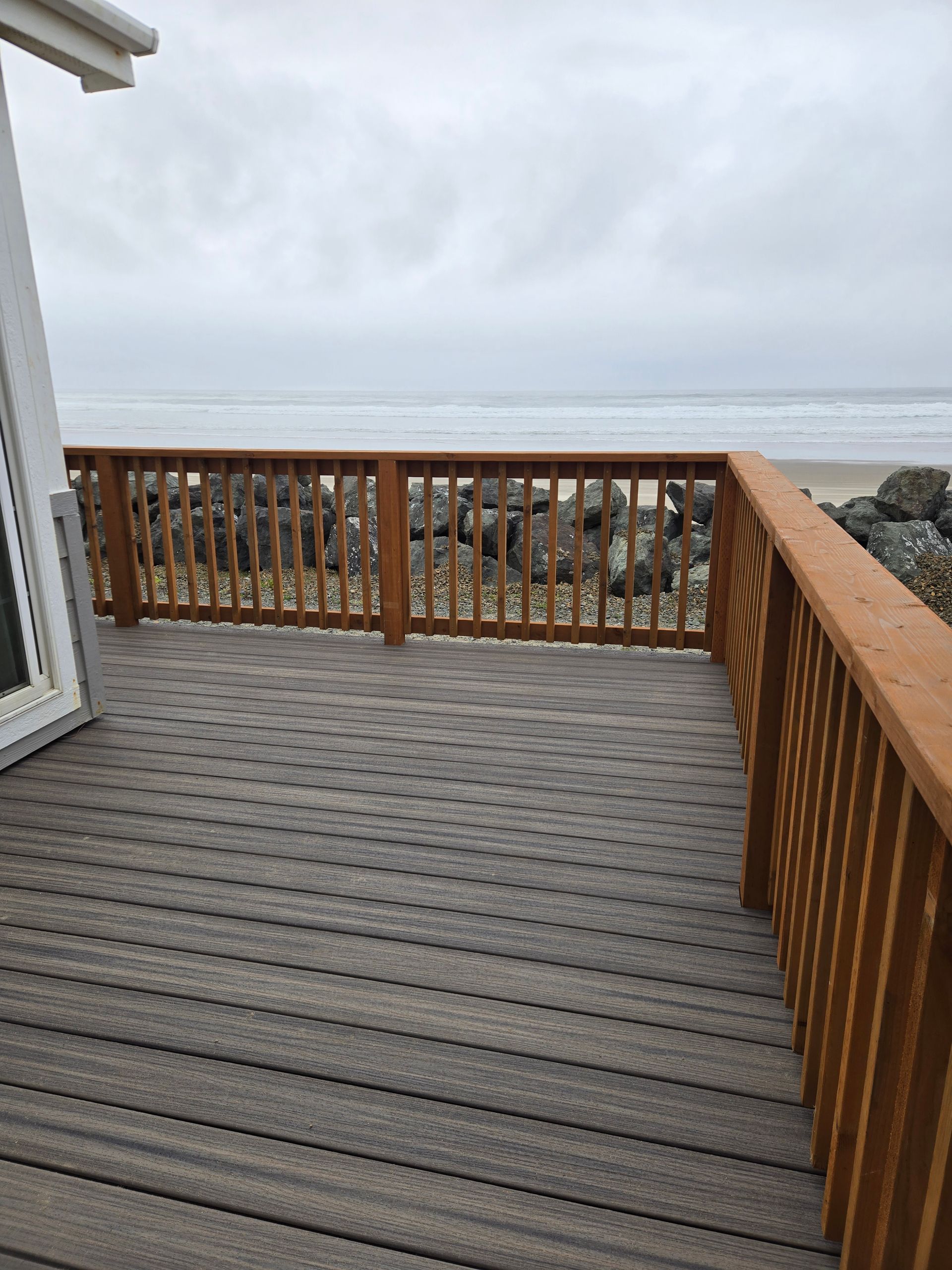 Wooden deck with railing overlooking a gray ocean under an overcast sky