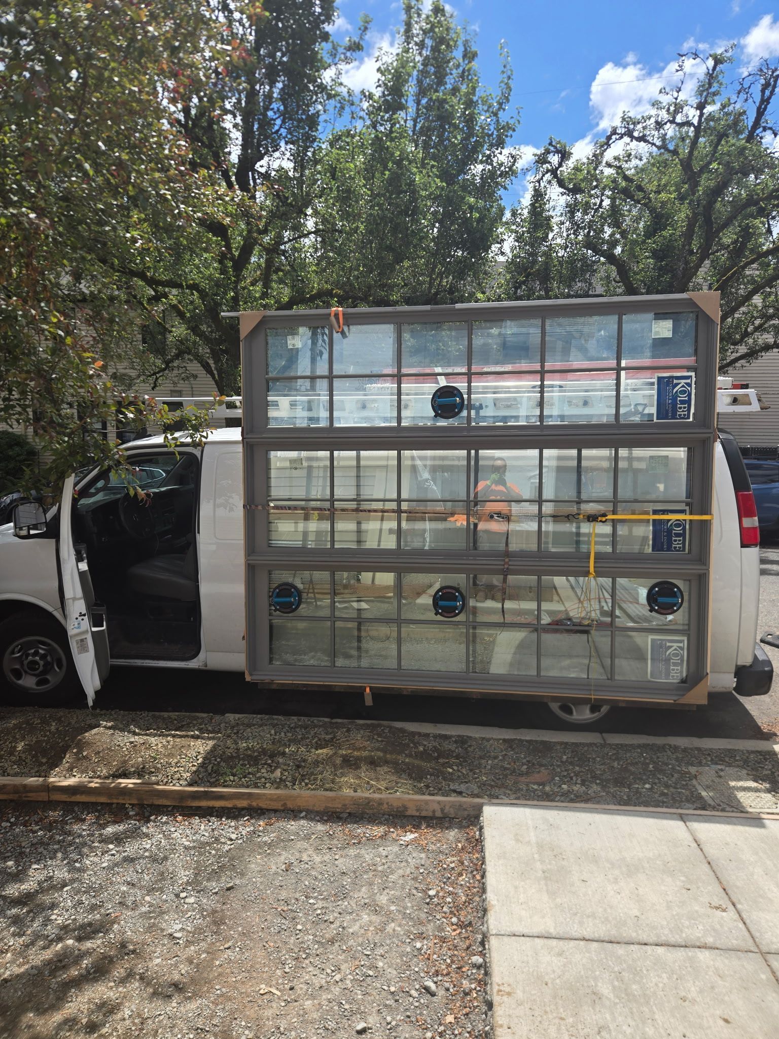 White van with side door open, carrying a metal shelving unit loaded with boxes and supplies outdoors.