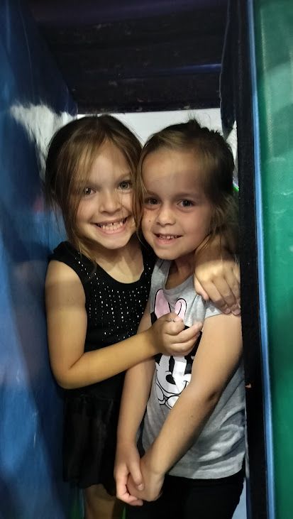 Two little girls are hugging each other in a play area.