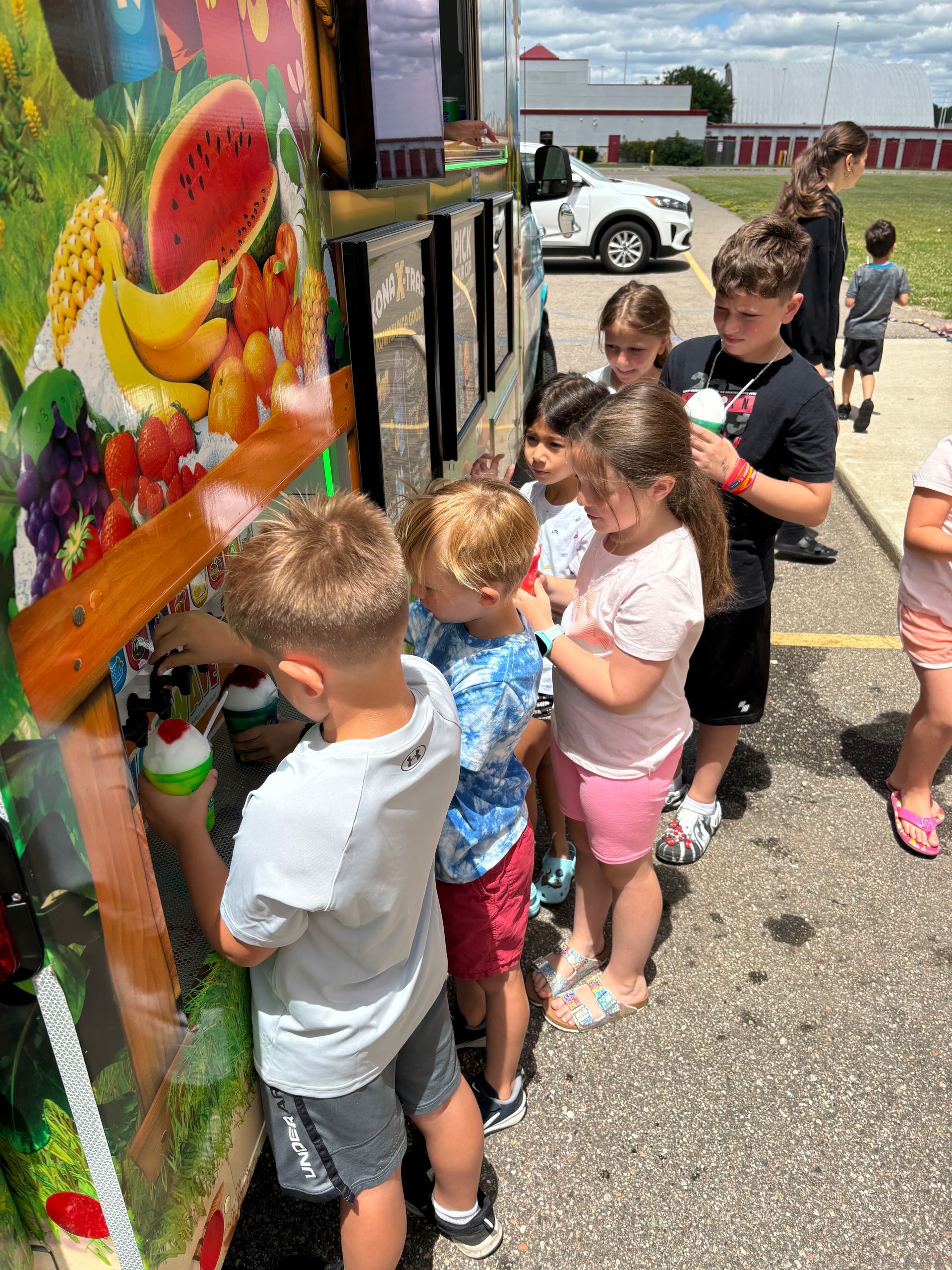 A group of children are standing in front of a fruit truck.