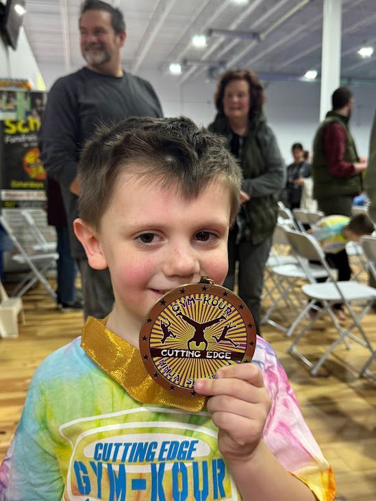 A young boy is holding a medal in his hand.