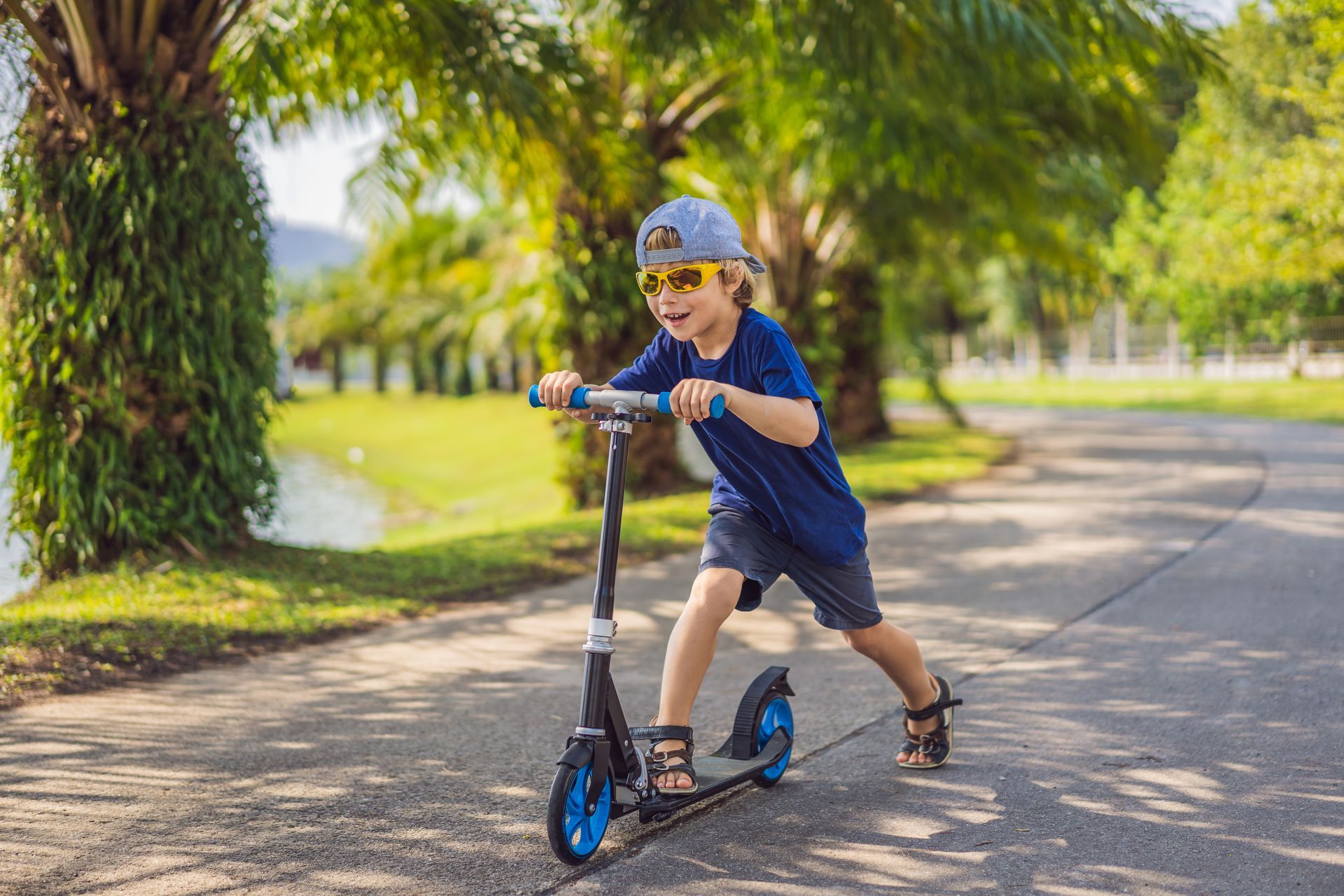 A young boy is riding a scooter down a road.