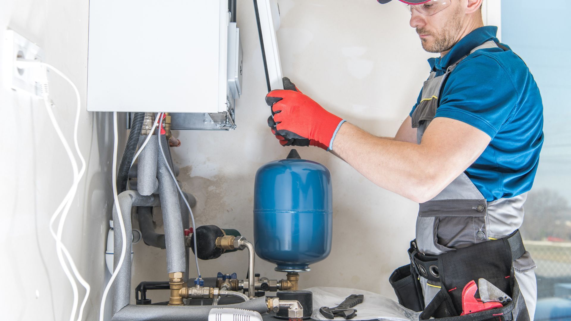 A man is working on a water heater in a house.