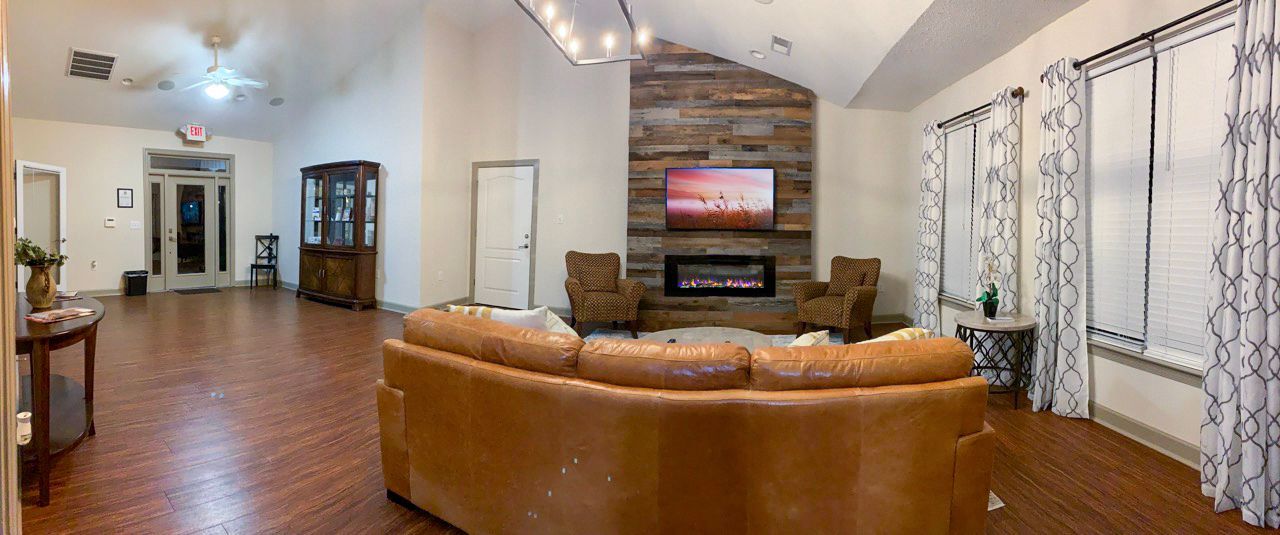 Spacious interior with leather couch, fireplace, and large windows with patterned curtains.