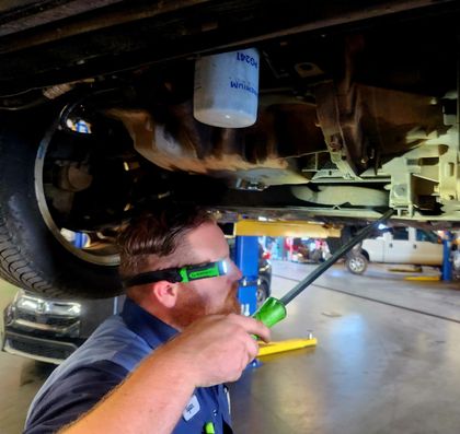 Mechanic under a car inspecting the oil filter | The KAR Shop