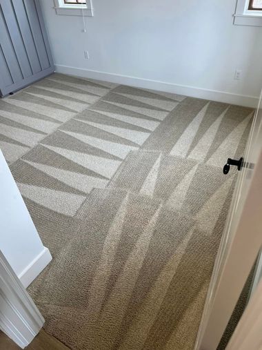 Empty carpeted room with light gray walls and doorway, viewed from the hall.