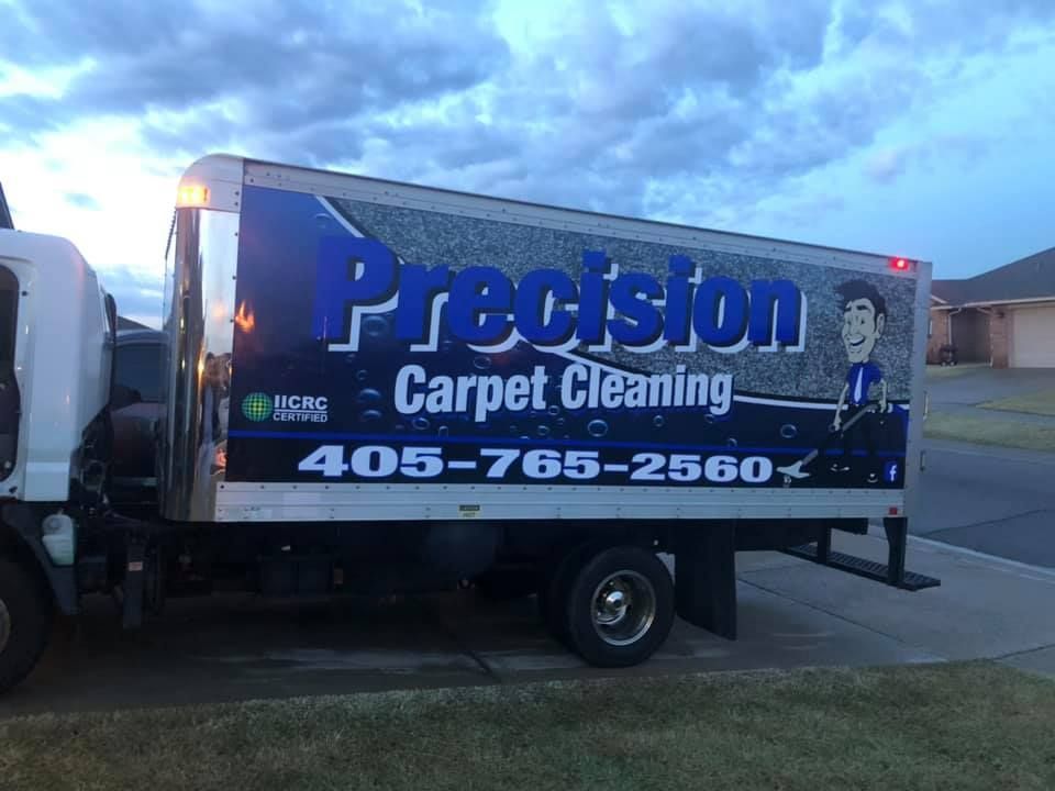 Precision Carpet Cleaning truck with blue logo and phone number parked outdoors at dusk