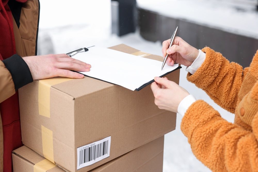 Two people packing a cardboard box and writing on a shipping label.