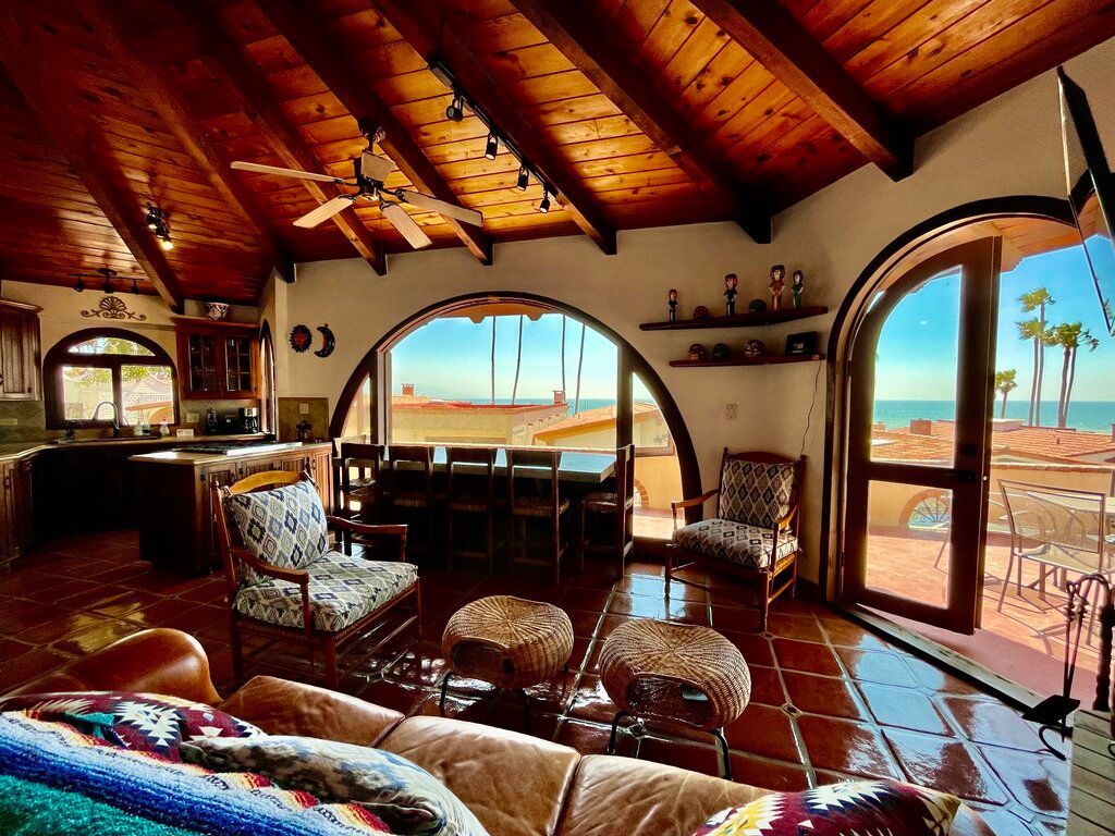 The living area with a sofa and chairs, plus a dining table, with a view out a large picture window