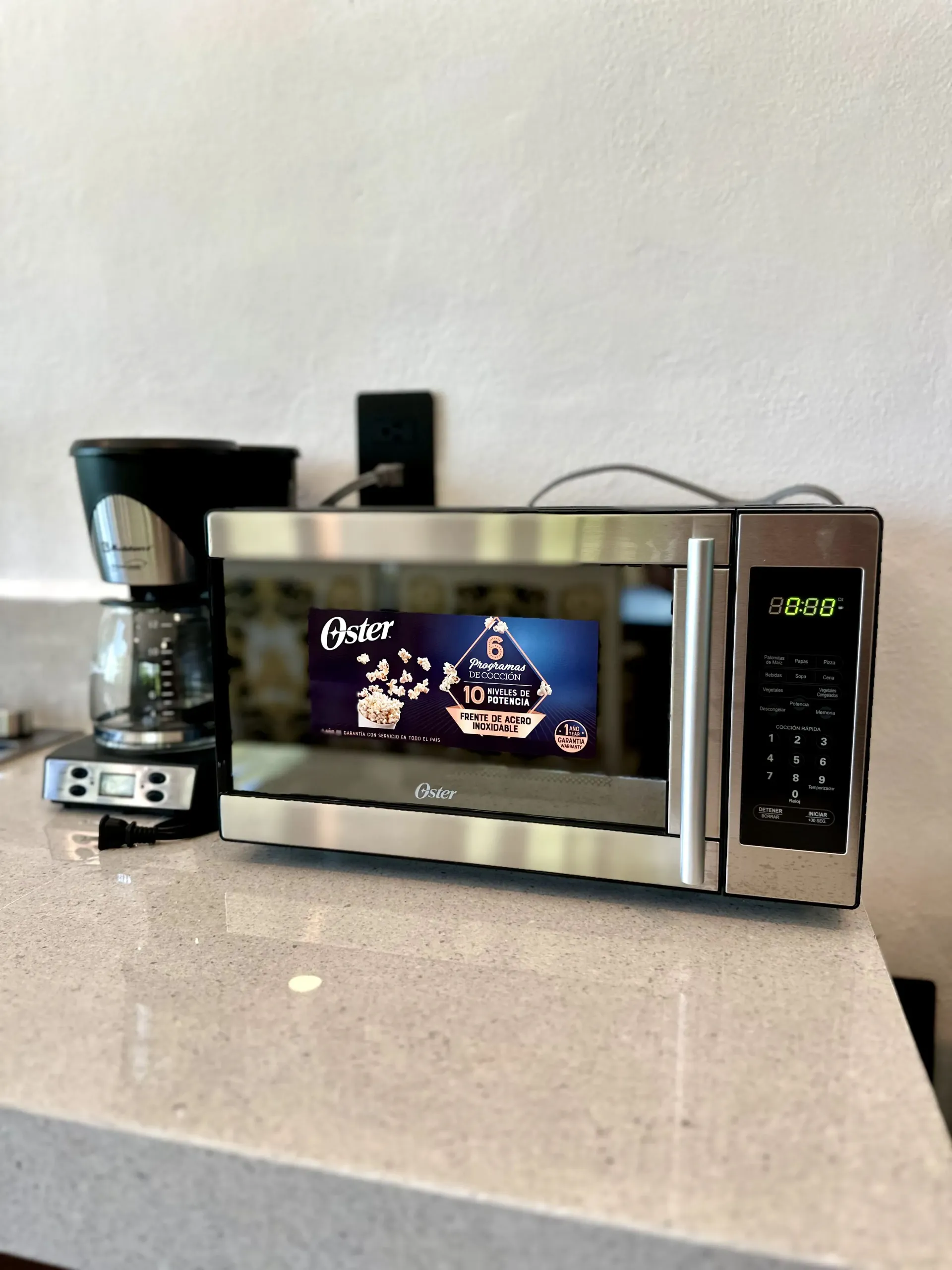 Microondas con pantalla digital, al lado de la cafetera, sobre la encimera.