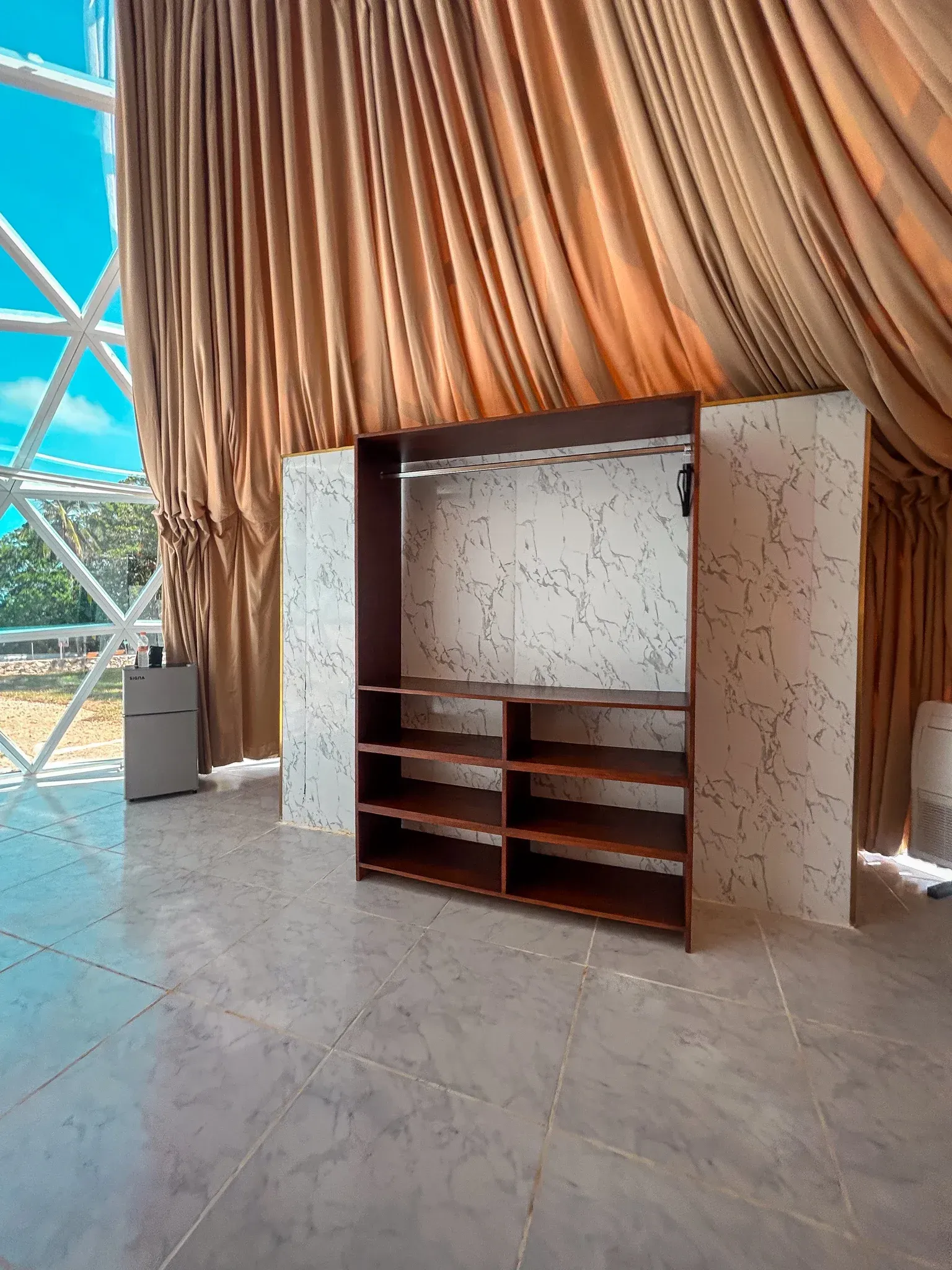 Estantería de madera con estantes y barra para colgar ropa sobre un fondo texturizado. 