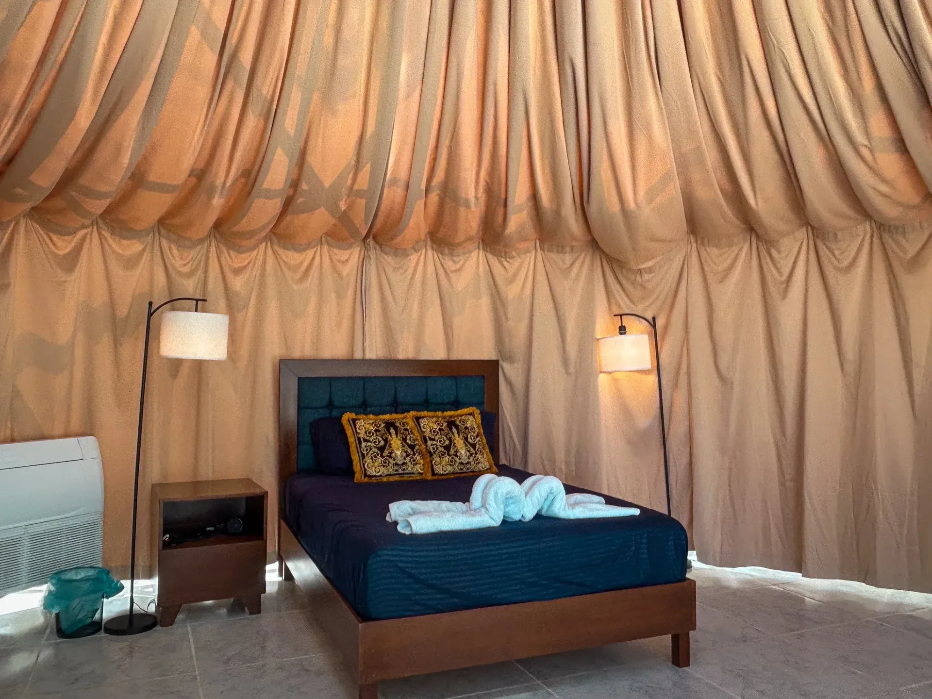 Interior de dormitorio con cama, lámparas y techo con cortinas.