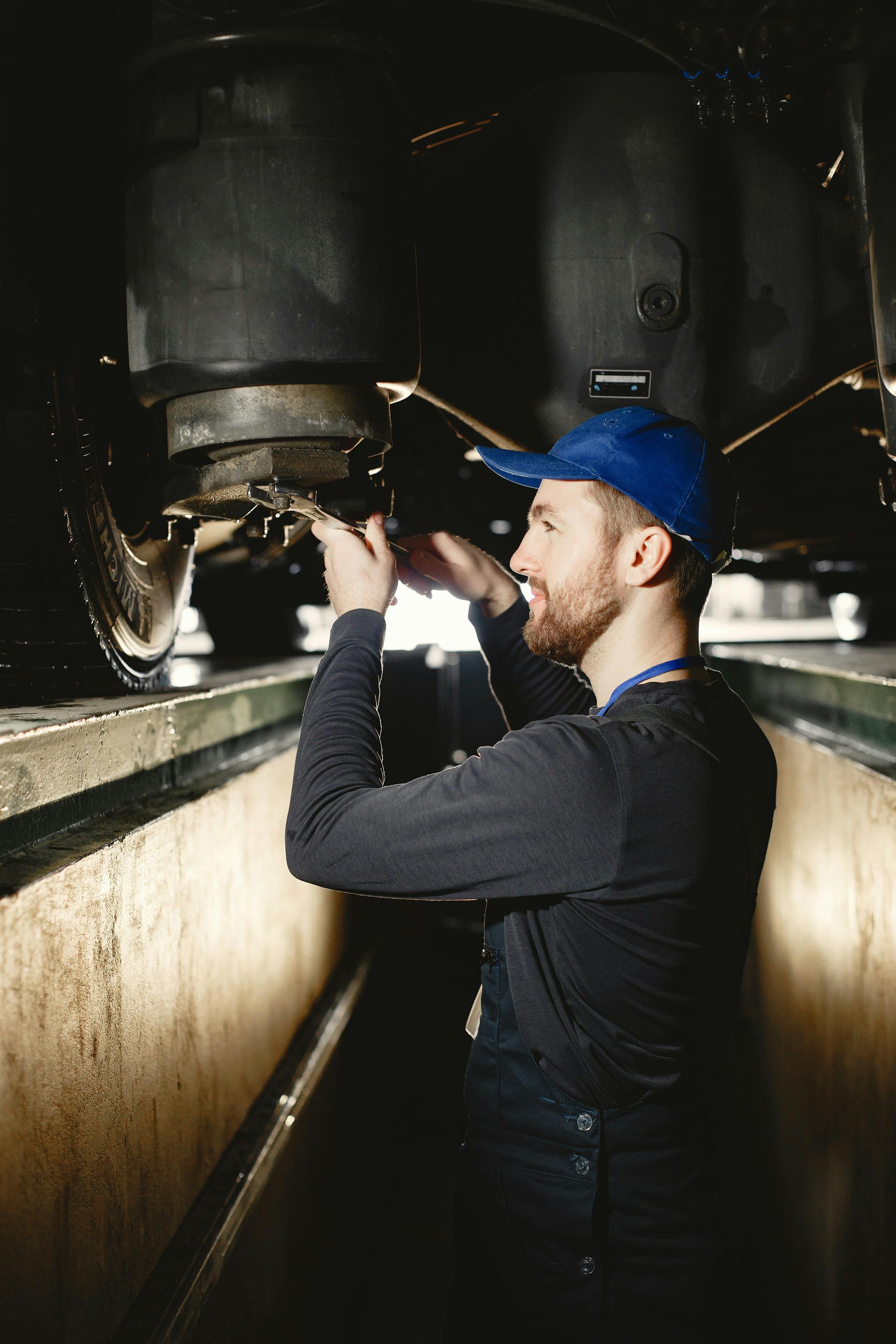 Worker inspecting machinery inside a large industrial tank, wearing a blue cap and dark overalls.