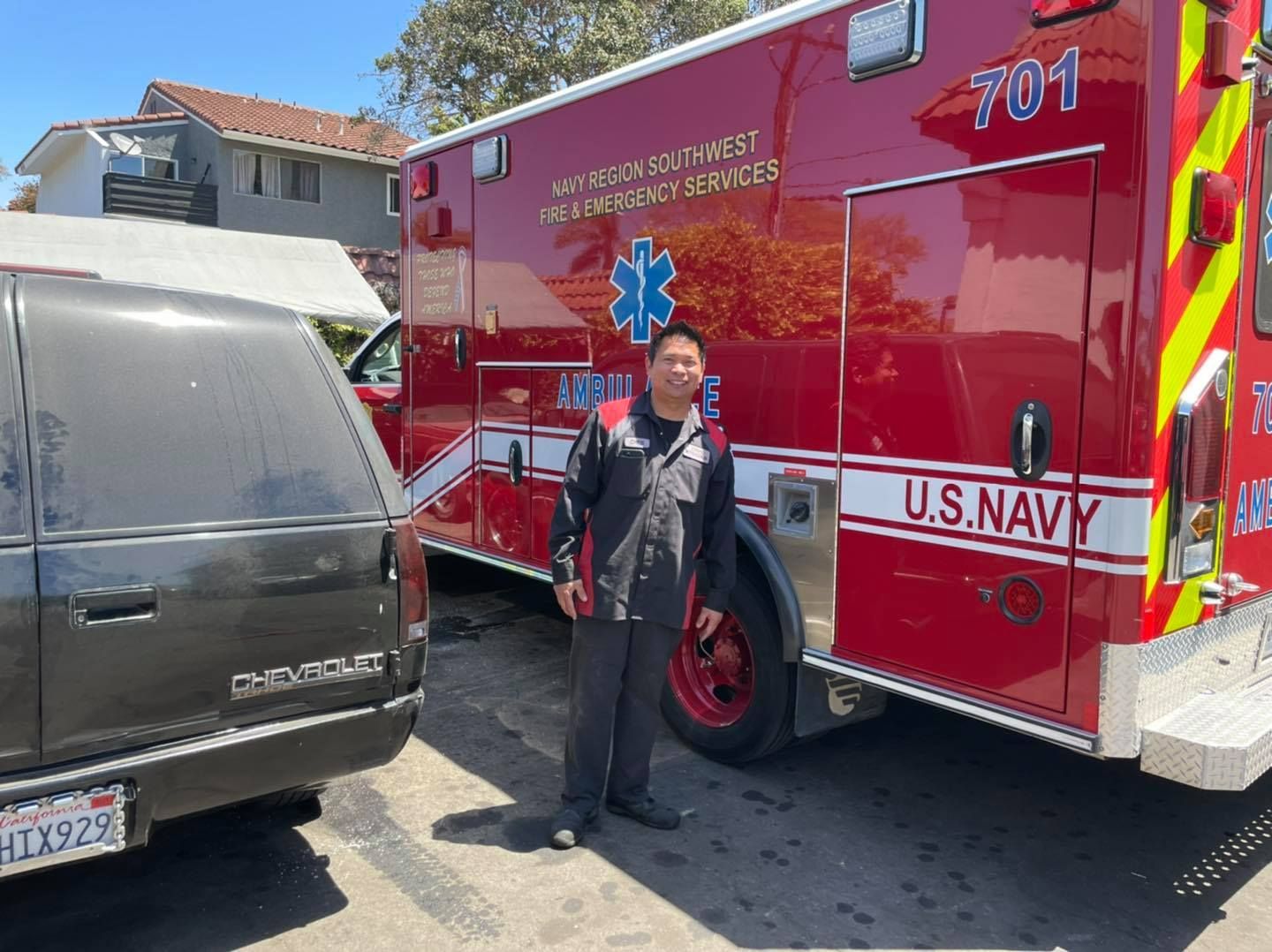 A man is standing in front of a u.s. navy ambulance.