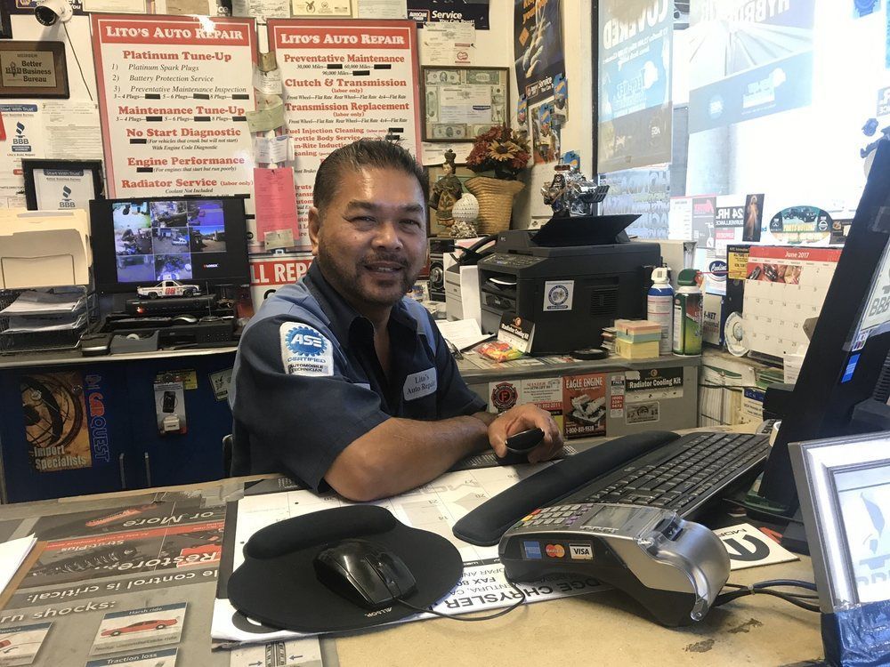 A man is sitting at a desk in a store using a computer.