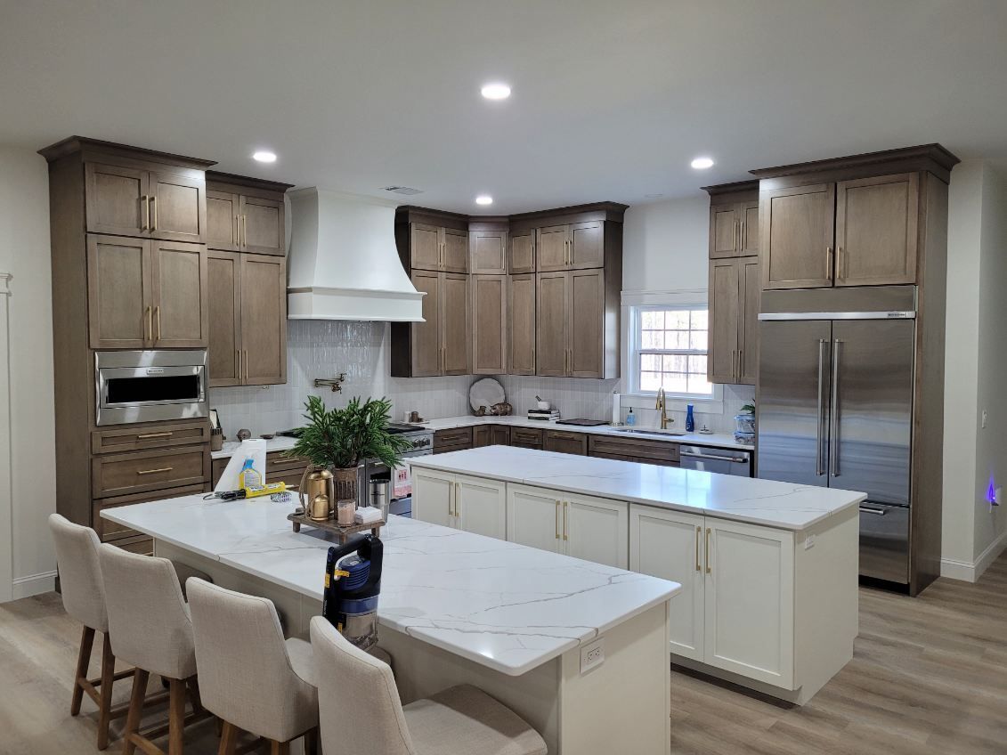 A kitchen with wooden cabinets , white counter tops , stainless steel appliances and a large island.