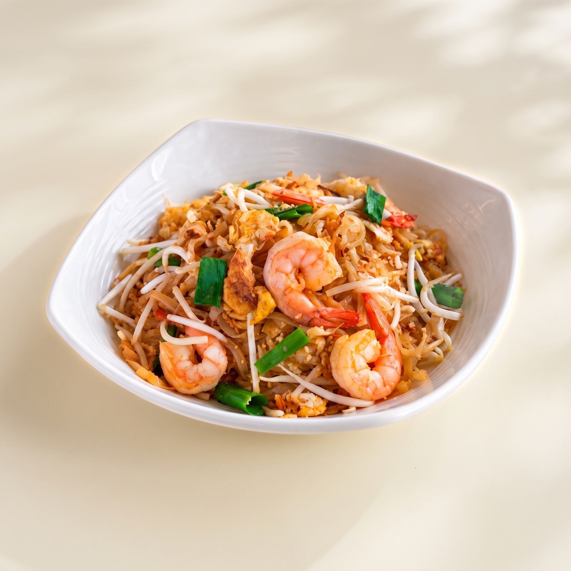 Shrimp fried rice in a white bowl with bean sprouts and green garnish