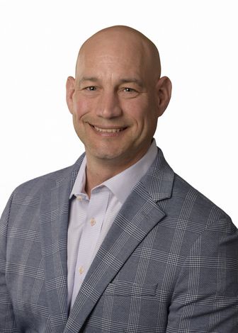 A man in a suit and tie is smiling for the camera