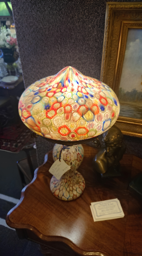 Colorful stained-glass table lamp on a wooden side table beside a framed picture.