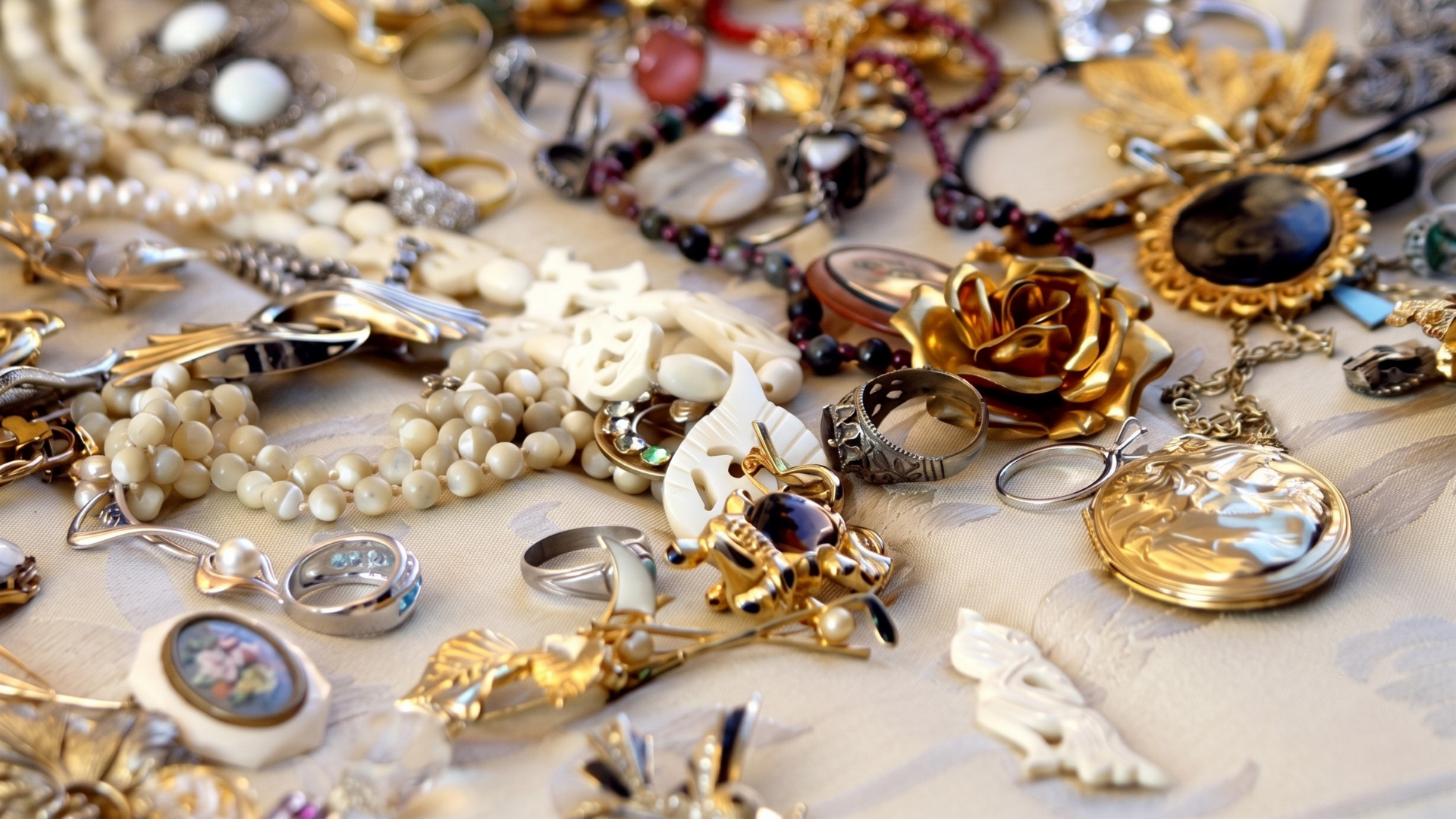 Assorted vintage jewelry and brooches, including pearl necklaces and jeweled flowers, arranged on a tabletop.