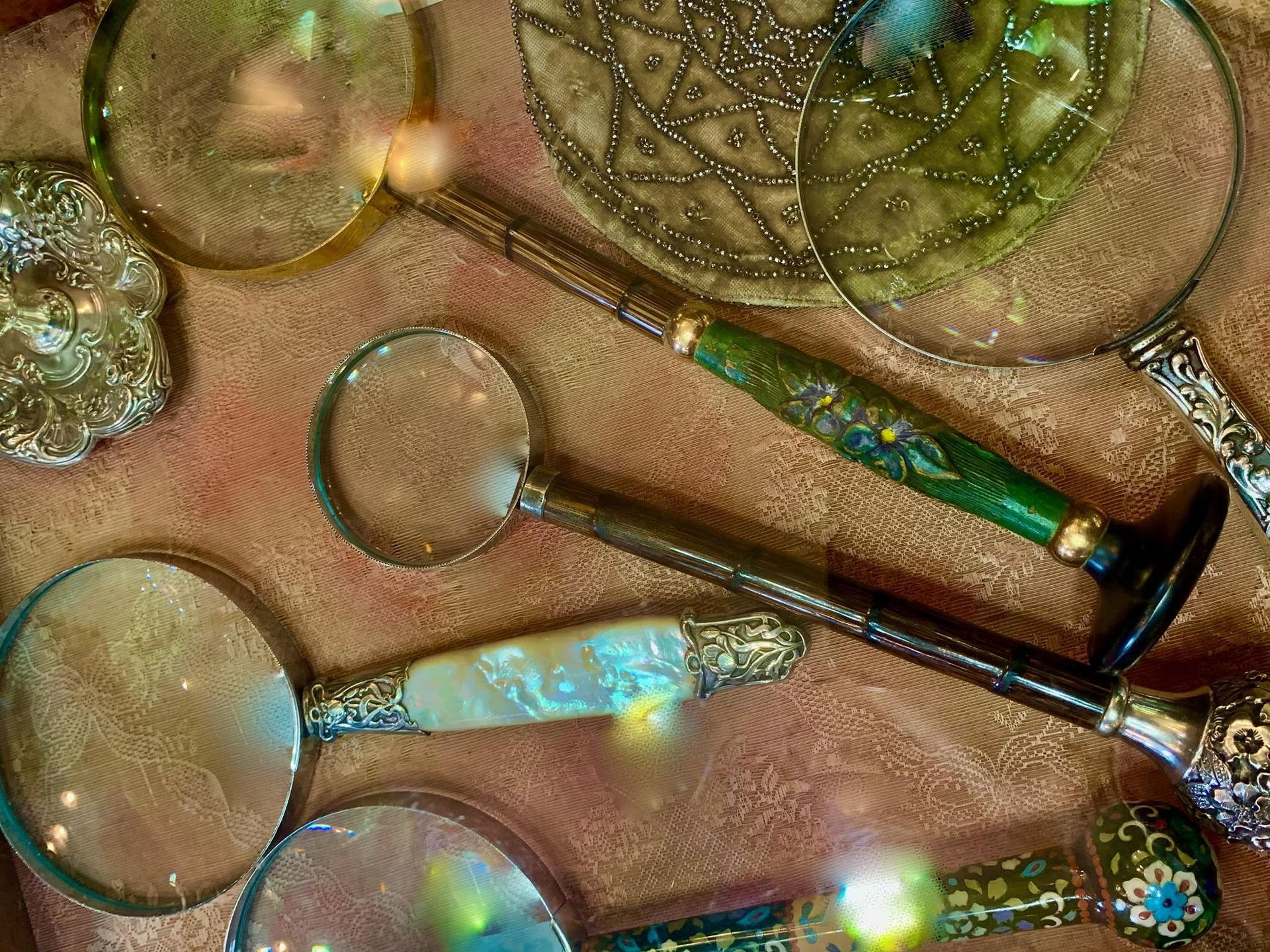 Assorted decorative magnifying glasses with jeweled handles on a textured surface.