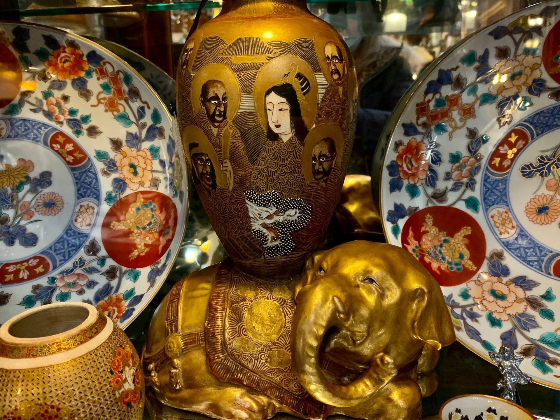 Decorative gold Buddha statue with ornate patterned plates and a small vase display