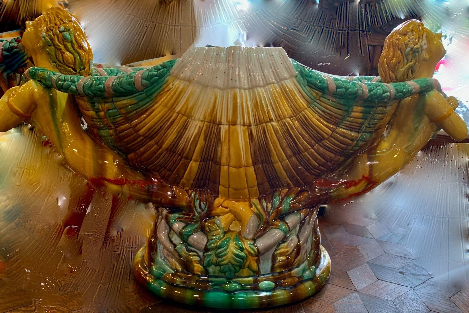 Ornate gold and green decorative fountain shaped like a shell with lion heads on a stone base