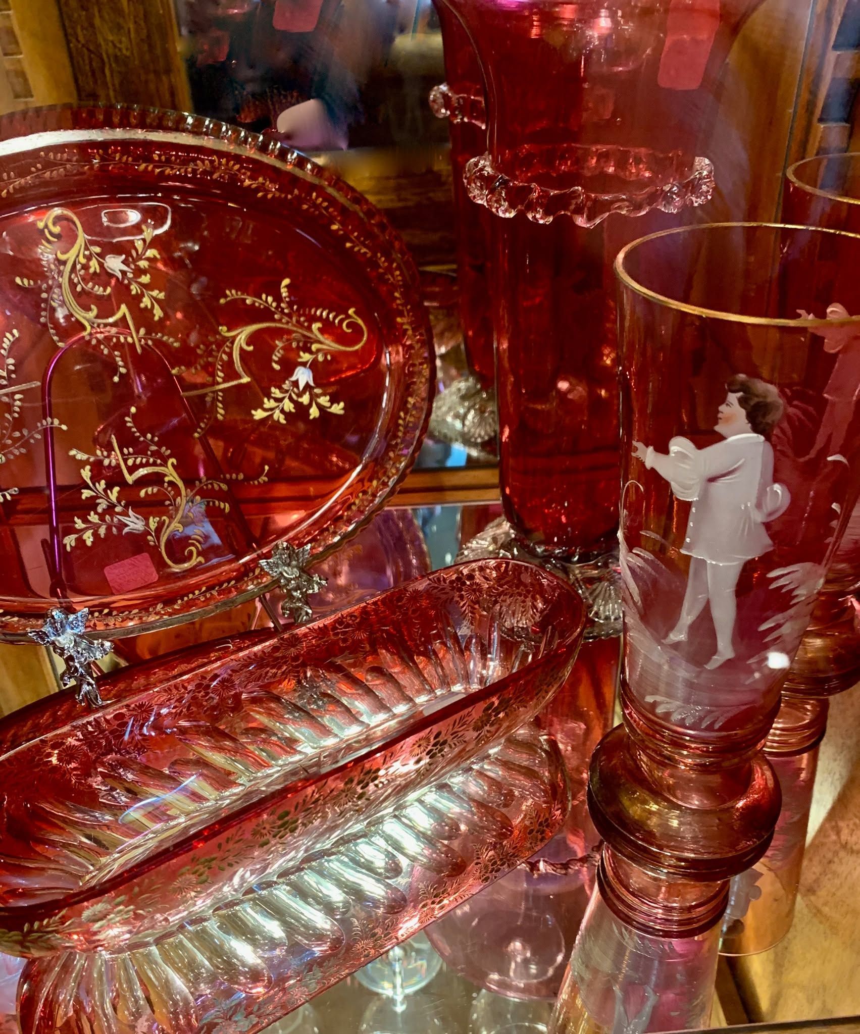 Red ornate glassware with gold accents and a white horse figure in a decorative display