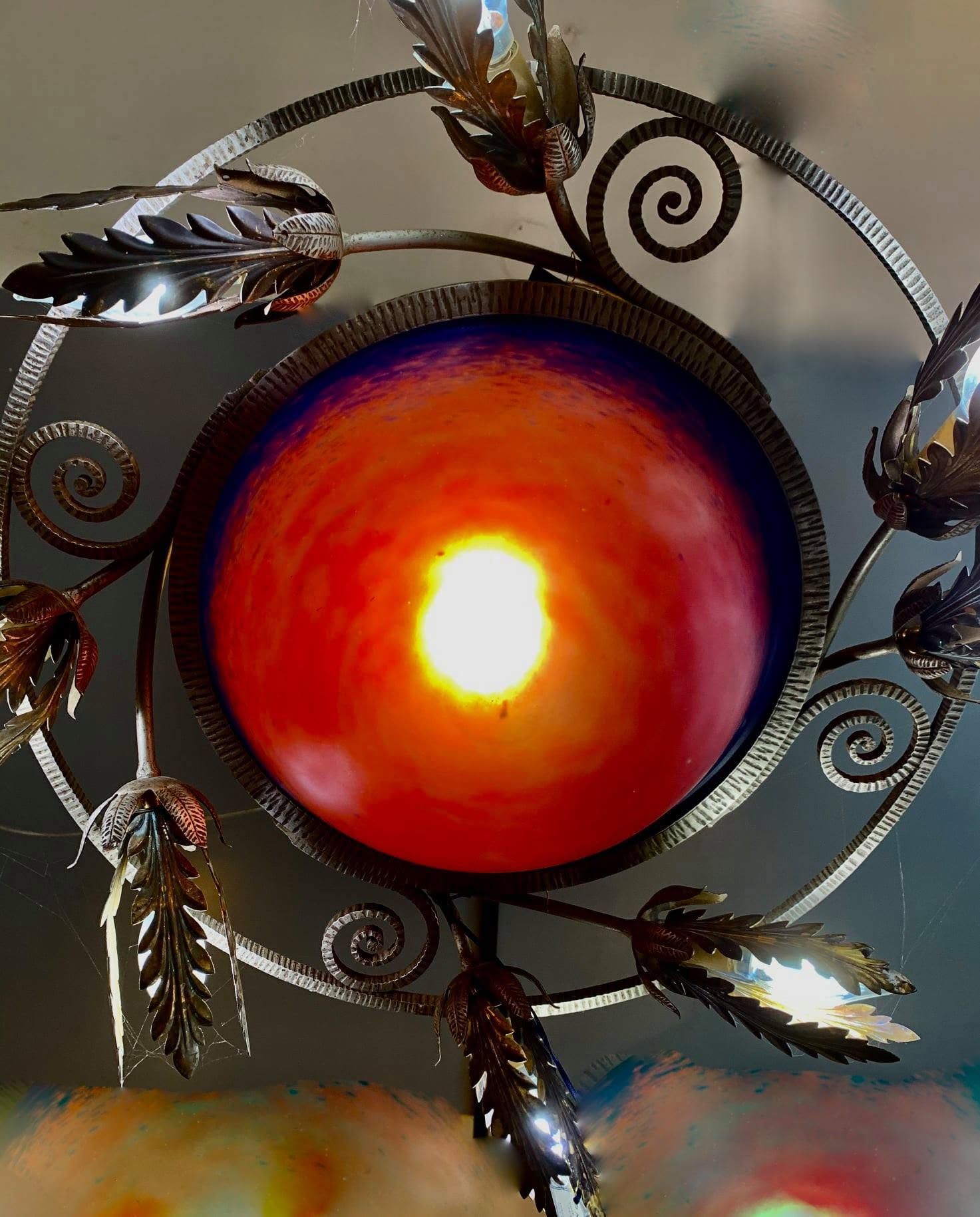 Red-orange glowing glass orb in ornate black metal swirls with leaf accents