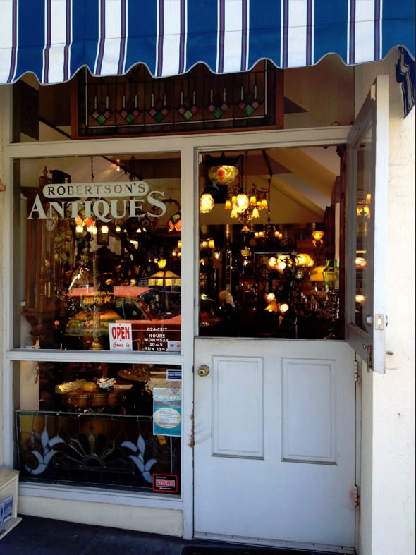 Antique shop storefront with striped awning and warm lights visible inside