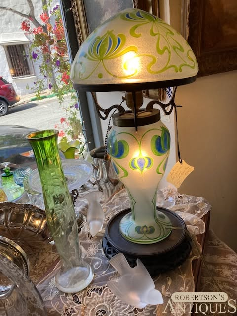 Decorative stained-glass lamp on a table, with green and yellow swirls and a matching shade.