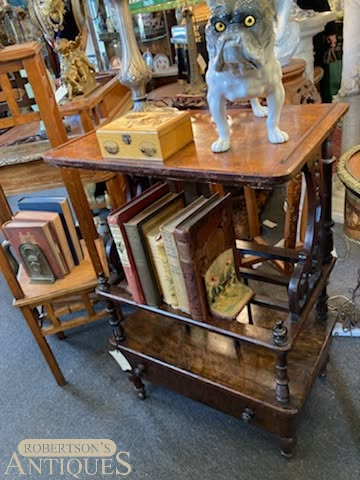 Gray cat figurine on antique wooden rolling book cart in an antique shop