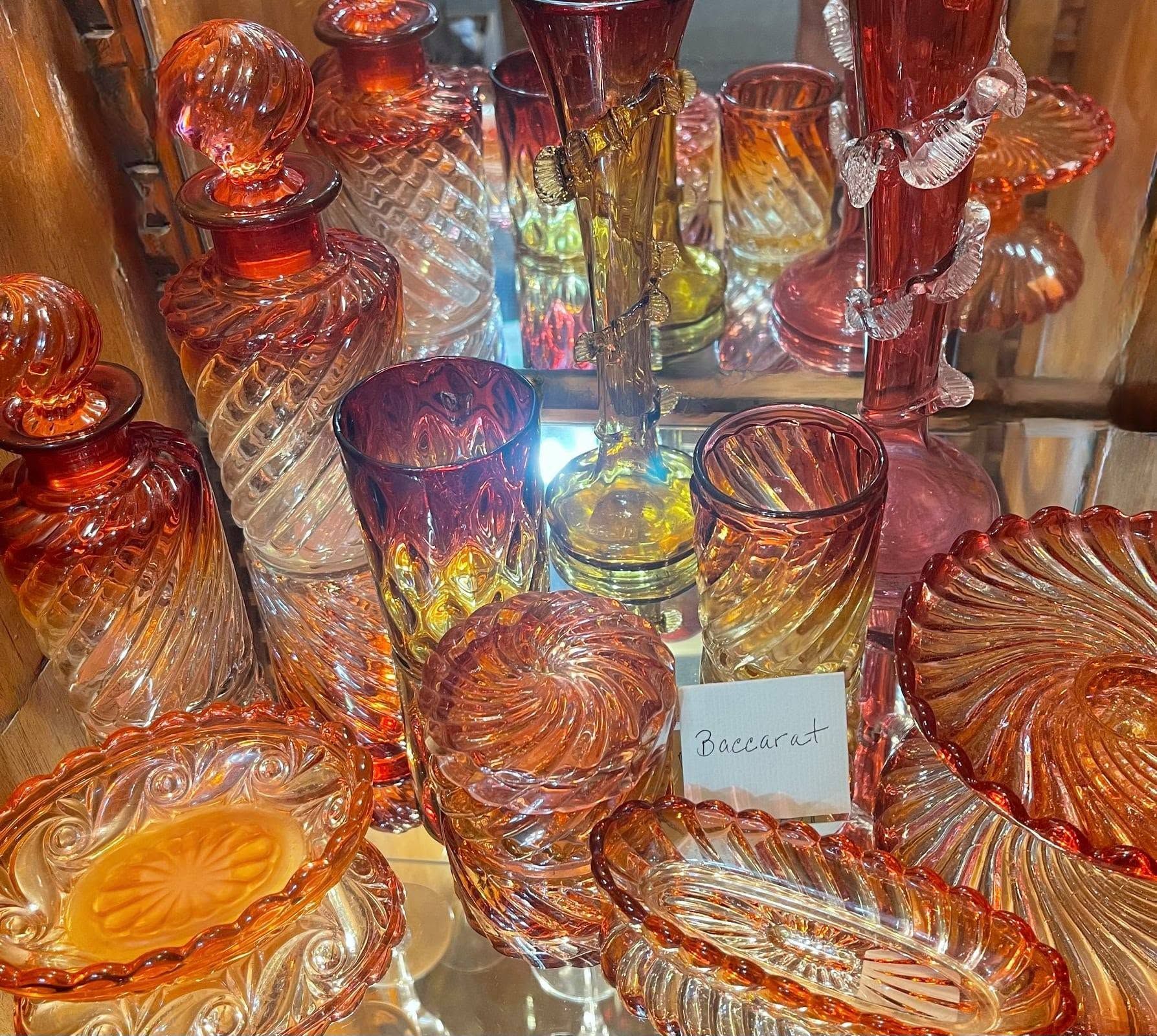 Assorted amber and red glass dishes and bowls displayed under bright lights.