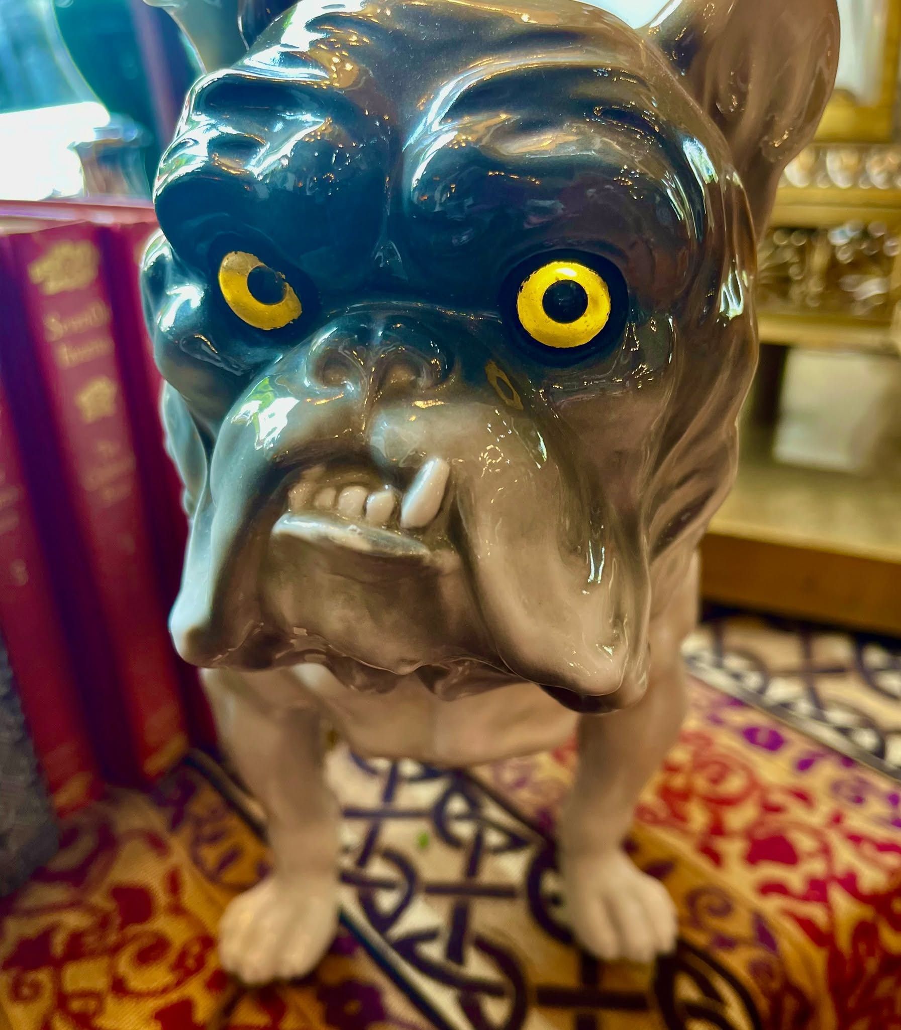 Bulldog figurine with yellow eyes on a patterned rug, indoors